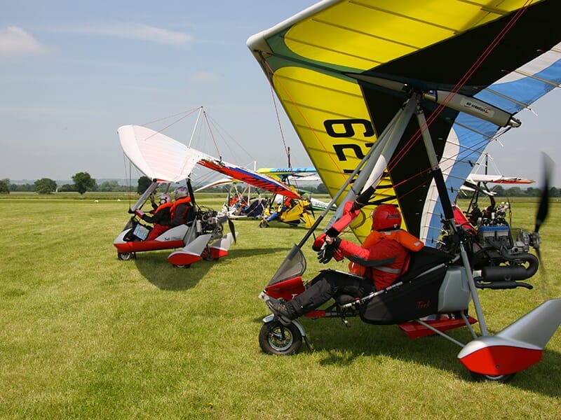 Plusieurs ULM pendulaire s'apprêtent à décoller sur la piste en herbe d'un aérodrome de province