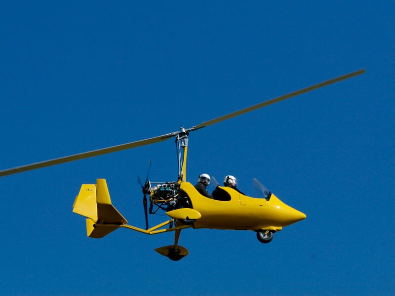 ULM autogire jaune en vol sur fond de ciel bleu