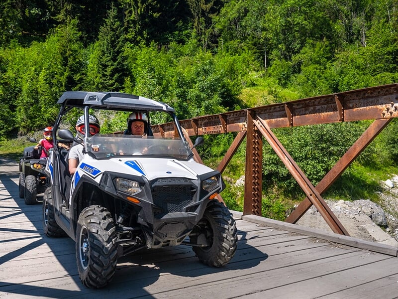 Un buggy franchit un pont sur un sentier escarpé dans les Alpes