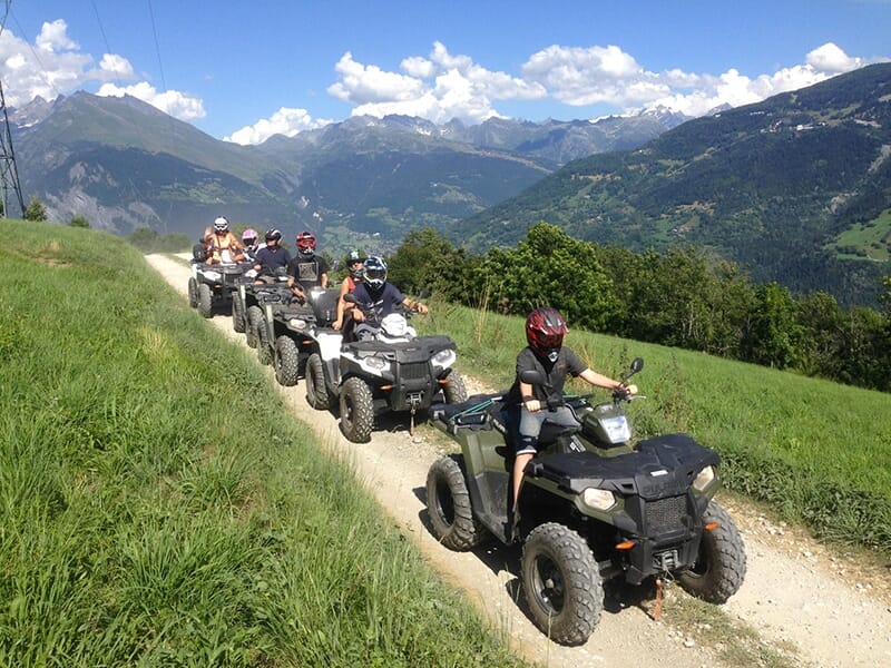 Un groupe de touristes circulent en quad sur un chemin de montagne dans les Alpes près de Bourg-Saint-Maurice