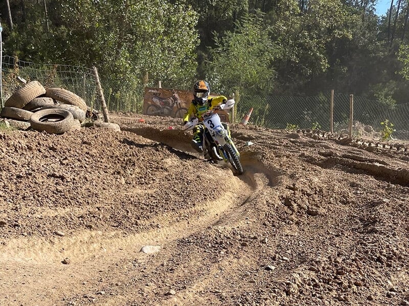 Un jeune pilote de motocross prend un virage ornière sur une piste en terre