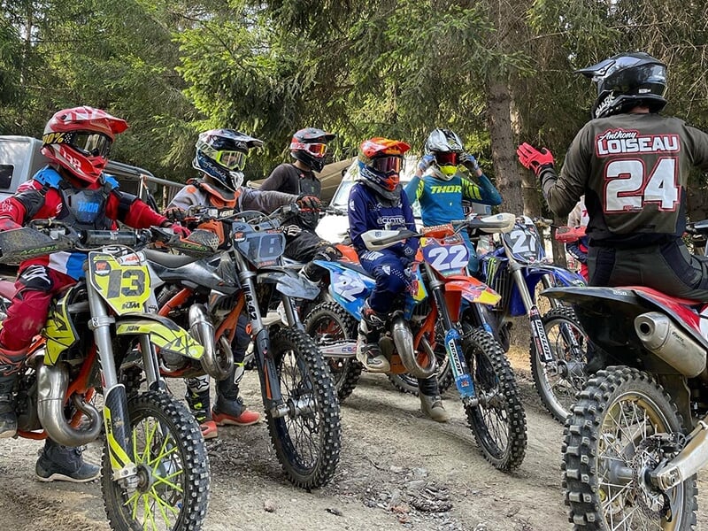 Un groupe de jeunes pratiquent la moto sous la vigilence d'un moniteur de motocross
