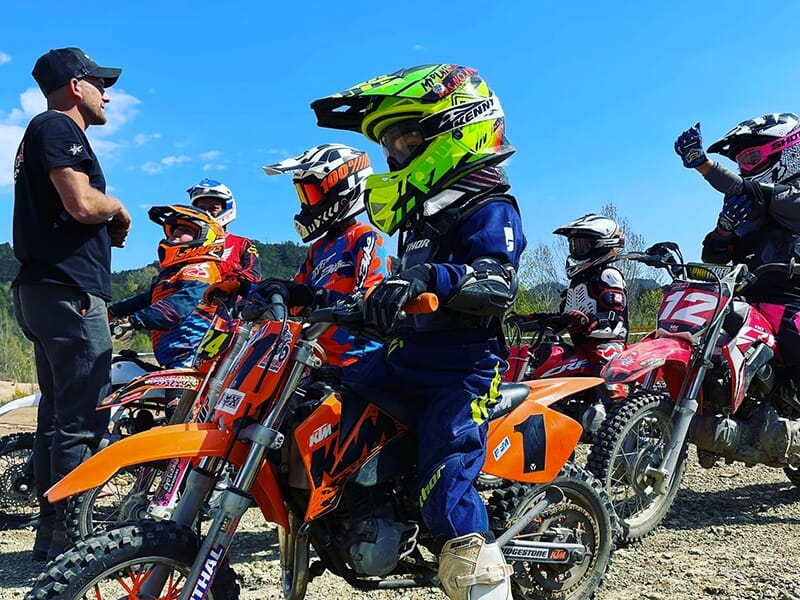 Un moniteur de pilotage briefe les participants d'un stage motocross pour les enfants