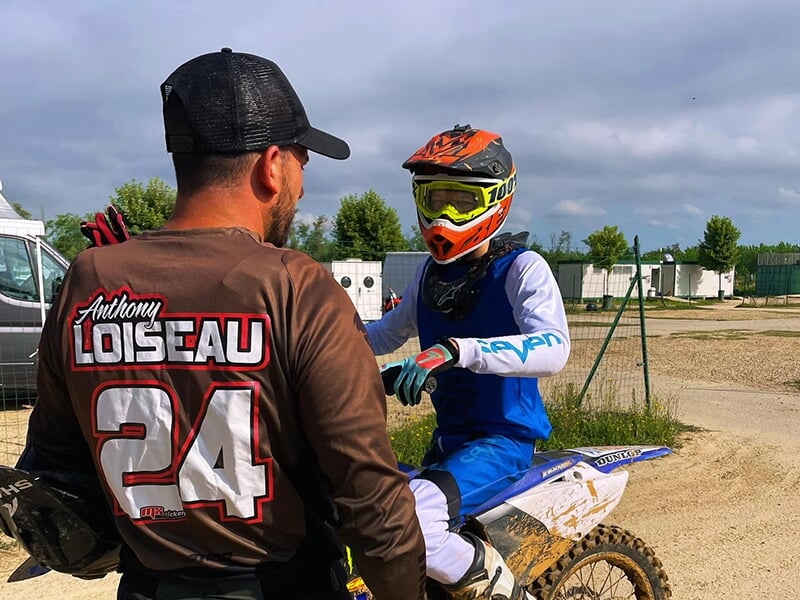 Un entraîneur de motocross coache un jeune pilote lors d'un stage de motocross