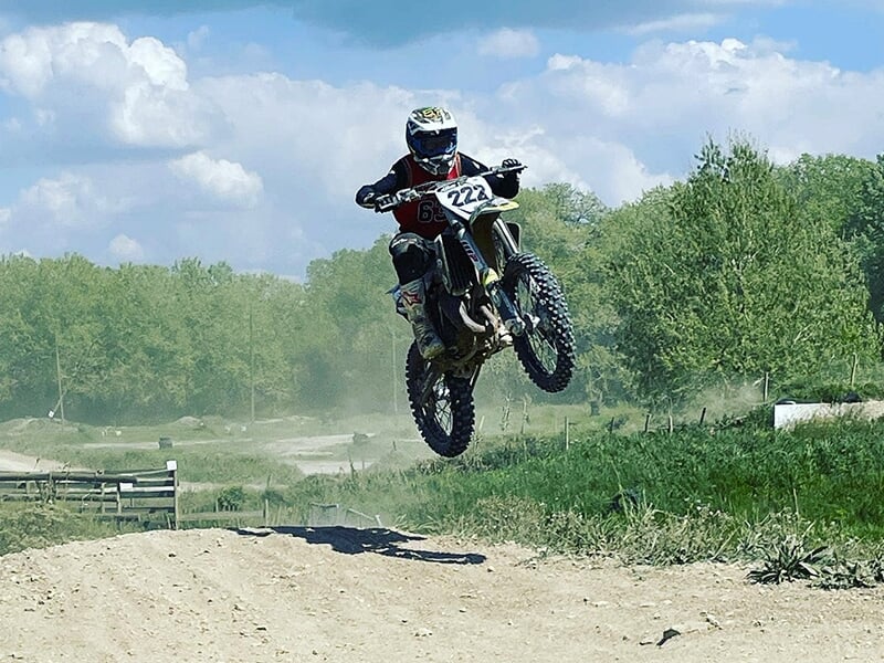 Un pilote de motocross effectue un saut sur une bosse d'un circuit tout terrain