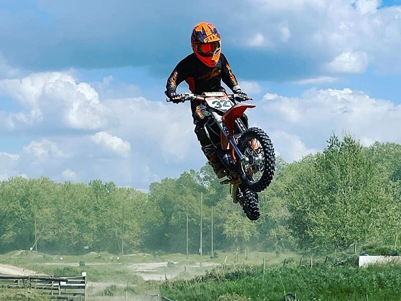 Un pilote de motocross en suspension après un saut sur une piste en terre