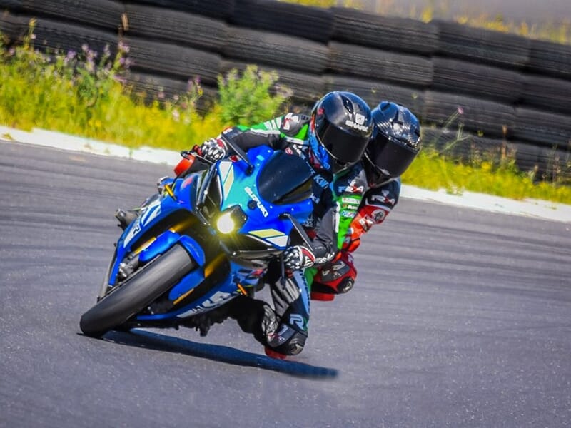 Deux motards en tenue complète sur une moto bleue prenant un virage serré sur circuit au Driving Center du Castellet.