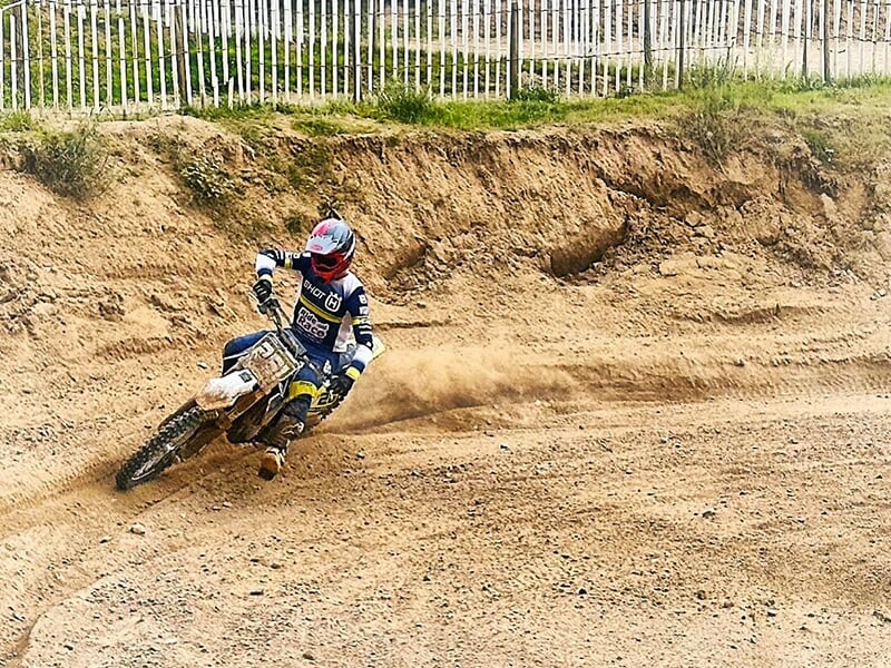 Un pilote de motocross négocie un virage ornière sur une piste en terre en Bourgogne-Franche-Comté