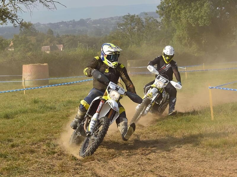 Des pilotes de motocross dans un virage serré sur une piste en terre