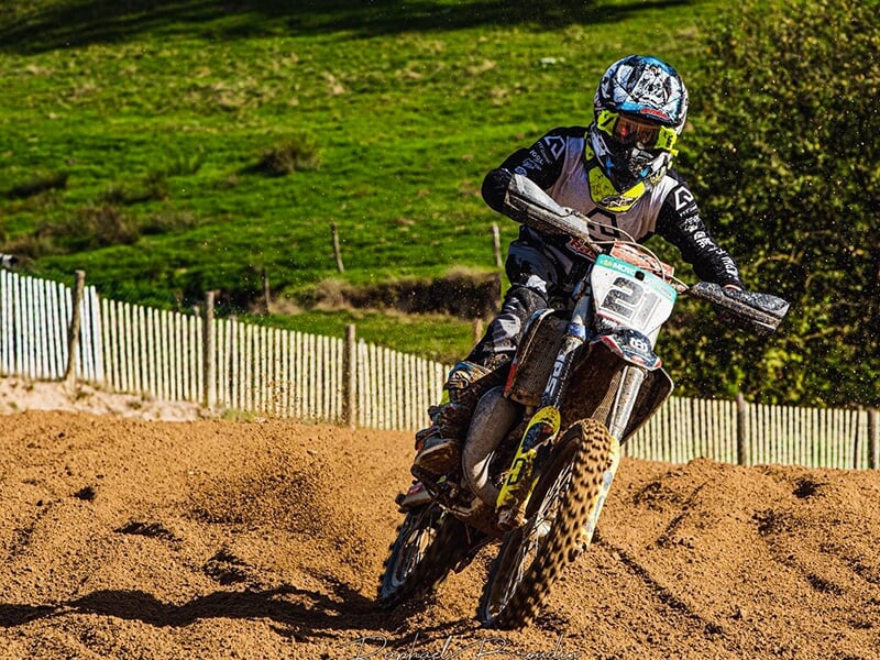 Un pilote de motocross négocie une montée sur une piste en terre 