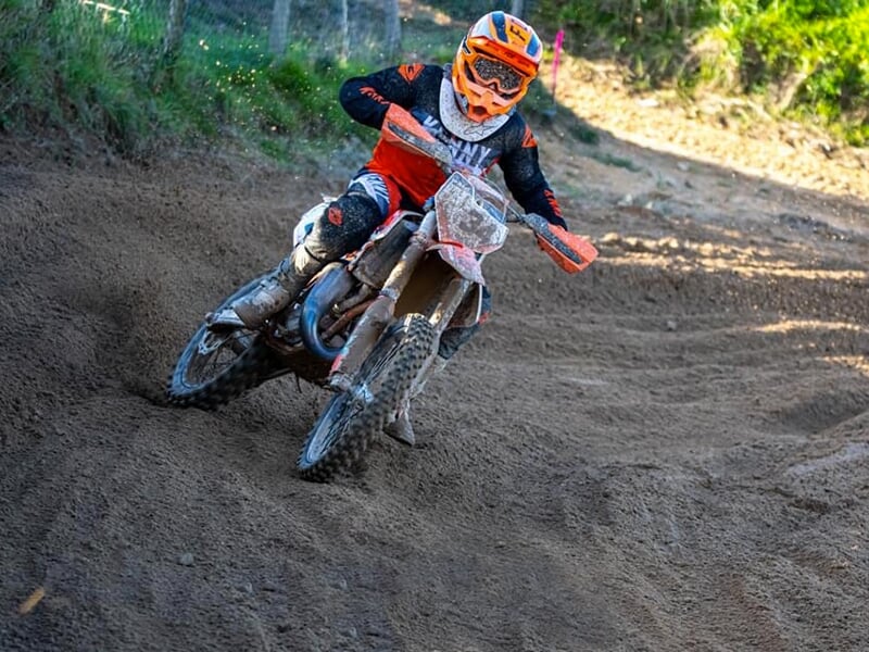Un pilote de motocross prend un virage sur un circuit en terre