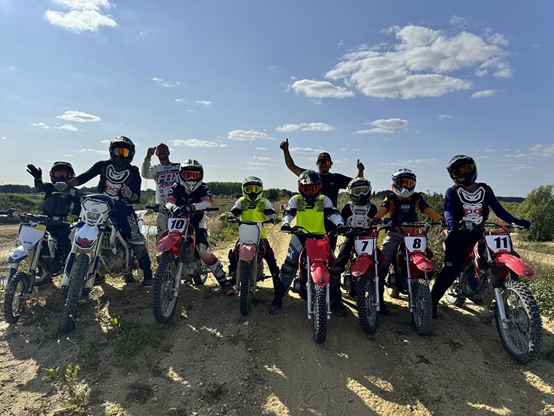 Groupe de motards alignés sur leurs motos tout-terrain, prêts à partir dans une compétition ou un entraînement en extérieur.