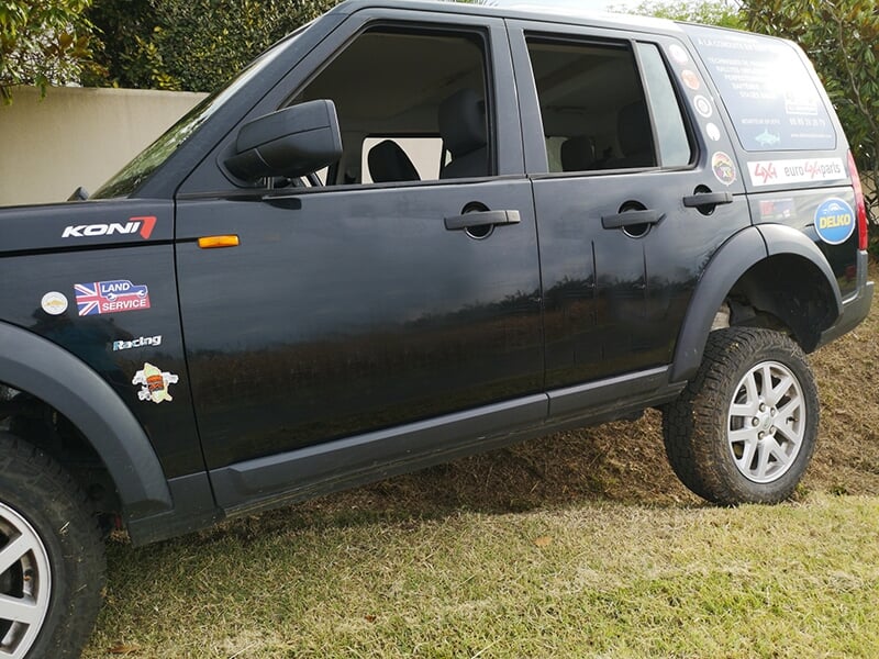 Un 4x4 Land Rover Discovery vu de côté sur une piste en terre