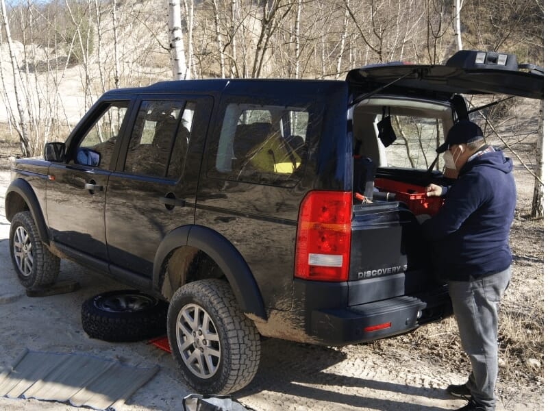 Un homme travaille à l'arrière d'un Land Rover noir Discovery sur un terrain sec lors d'un stage 4x4.