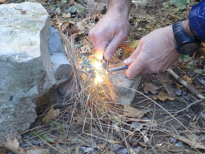 Un homme allume un feu sans briquet durant un stage de survie en autonomie dans la nature