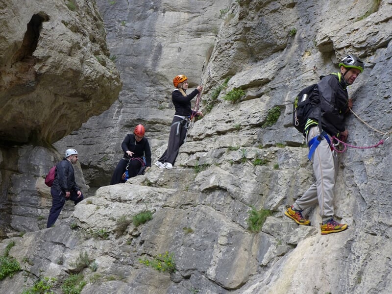 Un groupe de randonneurs progressent à flanc de falaise lors d'une via ferrata