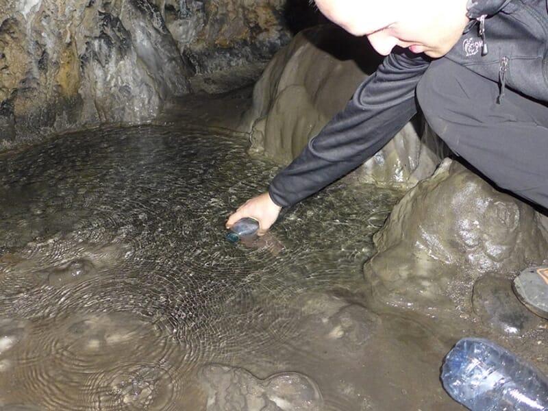 Un participant d'un stage de survie cherche de l'eau dans une grotte