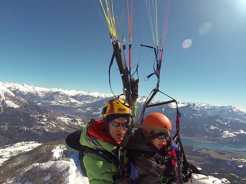 Deux personnes pratiquant le parapente au dessus du lac de Serre-Ponçon
