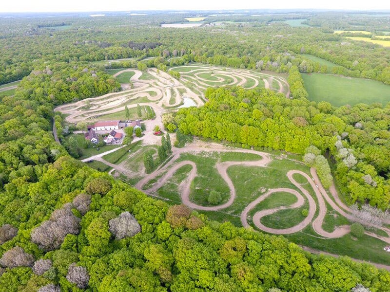 Vue d'une piste de motocross fraîchement labourée, prête pour une course, entourée de végétation.