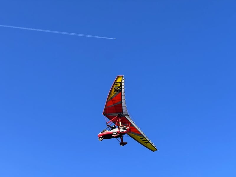 Un ULM pendulaire en plein vol dans un ciel bleu des Vosges