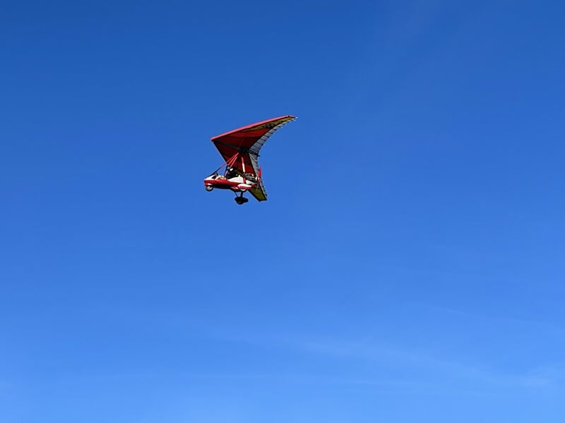 Un ULM pendulaire plane haut dans le ciel bleu des Vosges