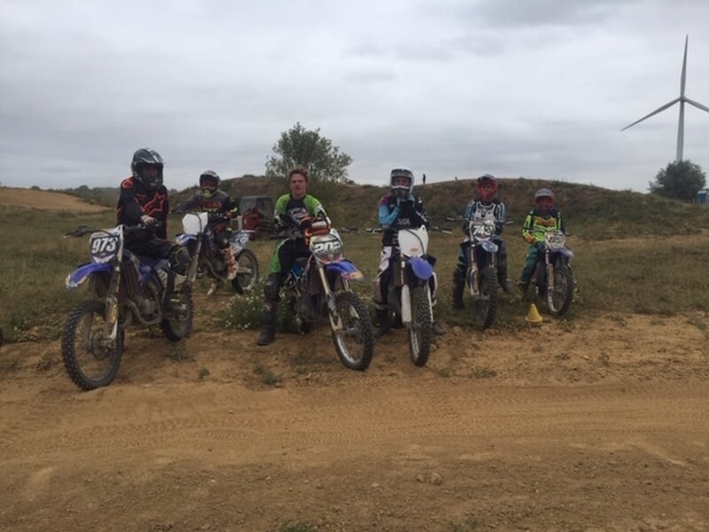 Groupe de personnes en moto-cross avec éolienne en fond
