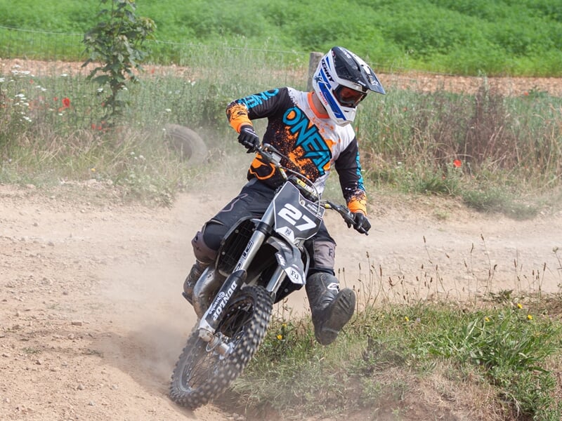 Adulte sur une motocross roulant sur un chemin de terre