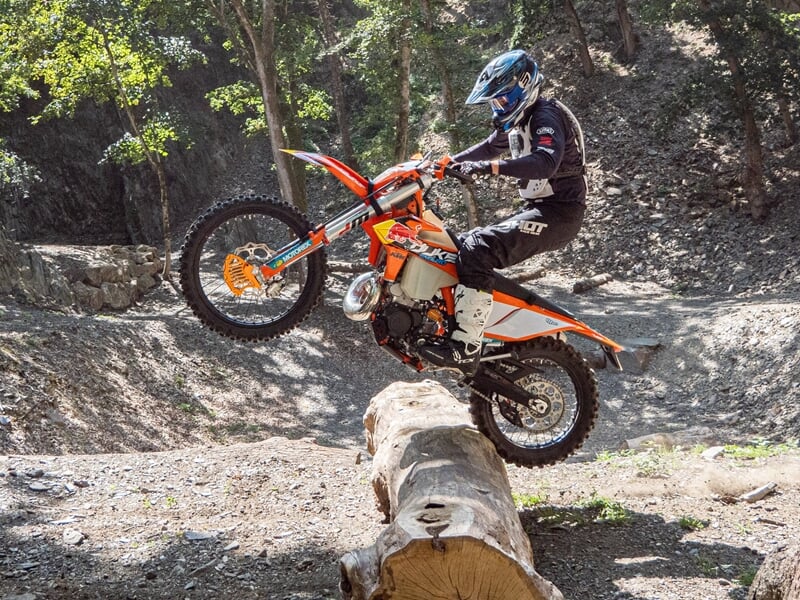 Personne franchissant un tronc d'arbre couché en moto cross