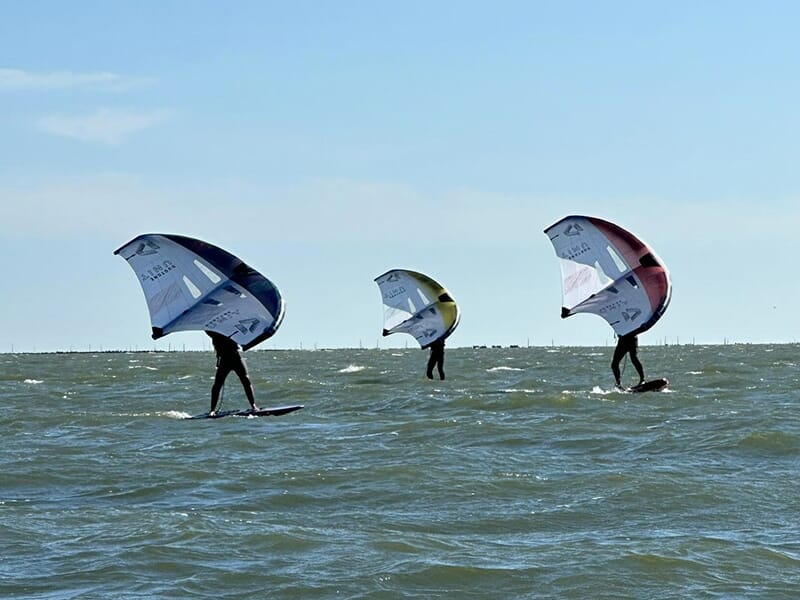 Un groupe de surfeurs pratiquent le wingfoil sur l'océan Atlantique