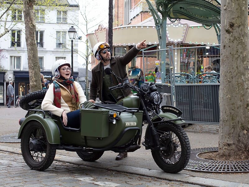 Un guide et une touriste dans un side-car vert vintage en balade dans Paris.