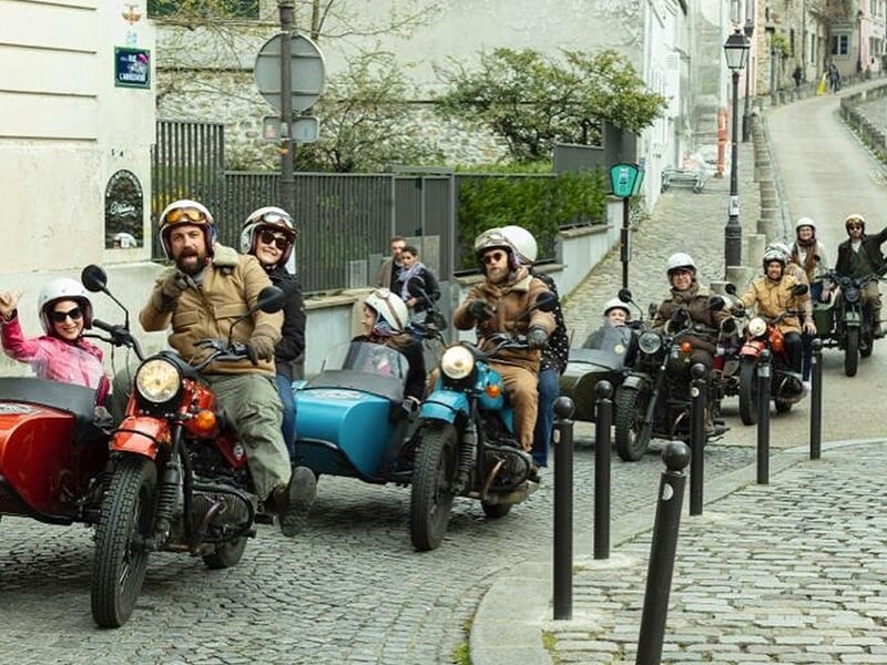 Groupe de personnes en balade sur plusieurs motos avec side-cars colorés dans les rues de Paris.
