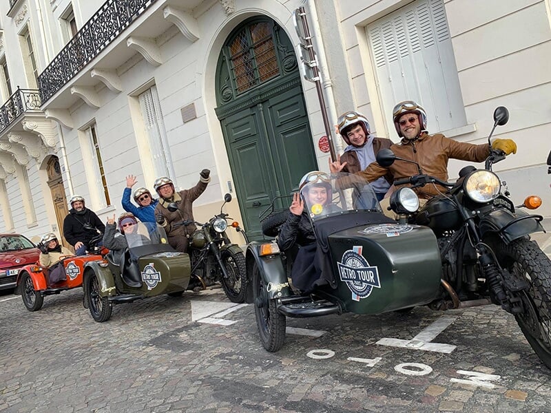 Groupe de motos rétro en side-car lors d'une excursion à Paris devant des bâtiments historiques.