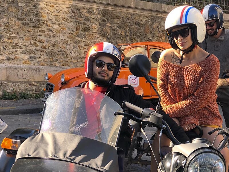 Deux personnes avec casque, prêtes à partir pour une balade en side-car dans Paris.