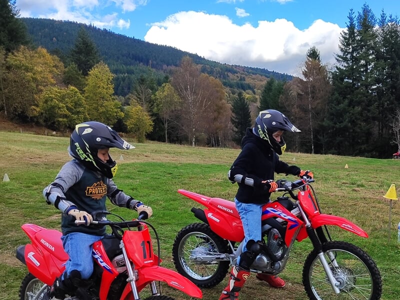 Deux enfants pratiquant la moto dans un pré à la montagne