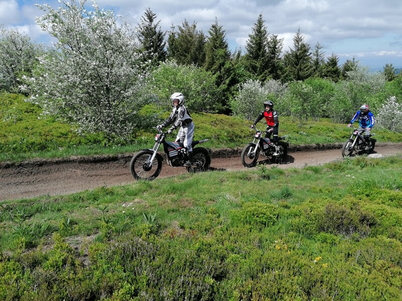 Trois personnes à moto sur chemin de campagne