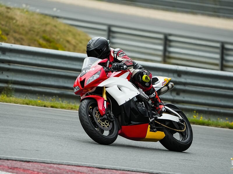 Moto rouge et blanche prise en pleine courbe sur une piste de course.