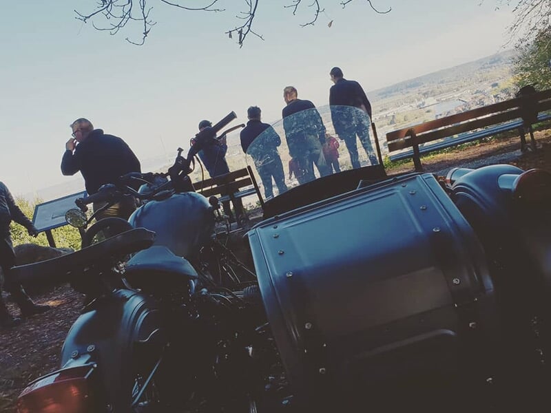 Des motos avec side-cars stationnées près d'un point de vue panoramique, avec des personnes observant le paysage au loin.