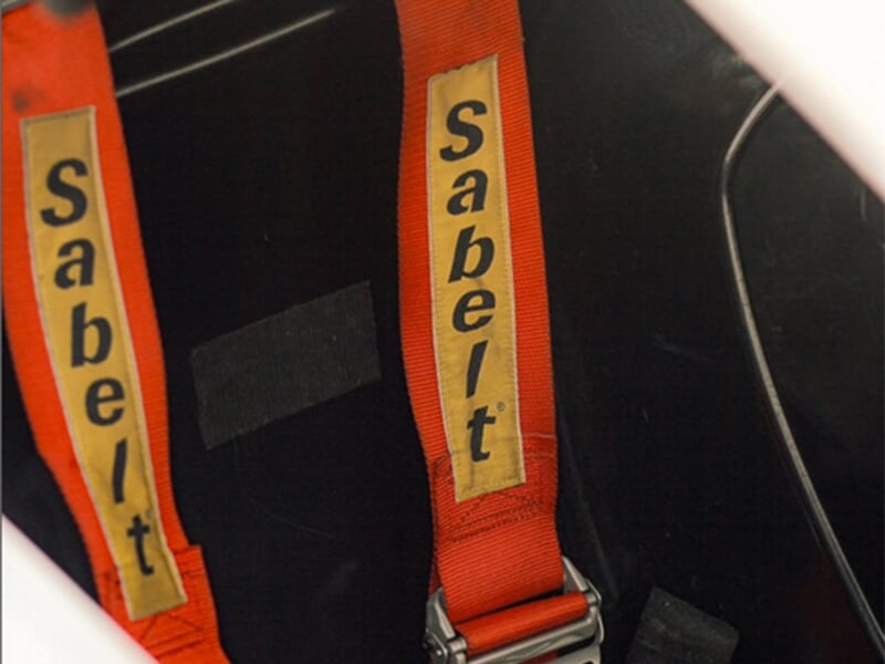 Harnais de sécurité rouge marqué 'Sabelt' dans un véhicule de course.