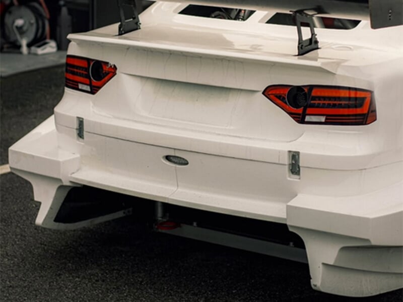 Arrière d'une voiture de course blanche avec un aileron.