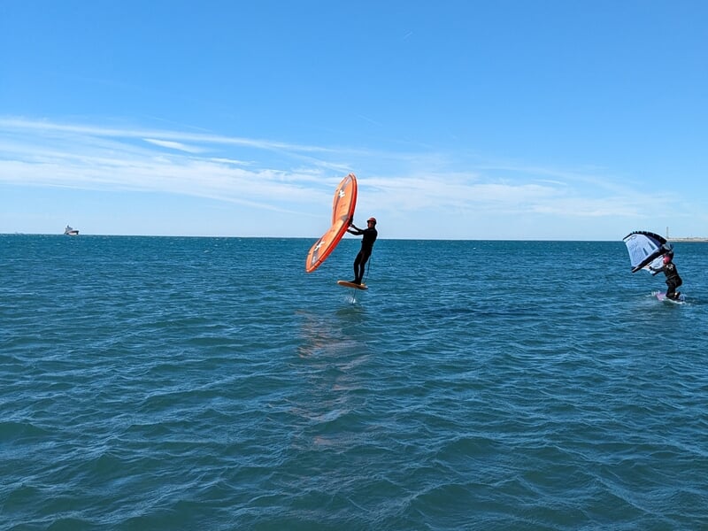 Deux personnes pratiquant le wingfoil sur la mer