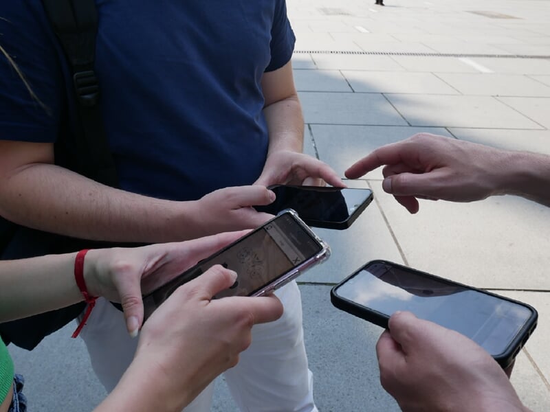 Groupe de 3 personnes réalisant un escape game outdoor avec smartphone en main