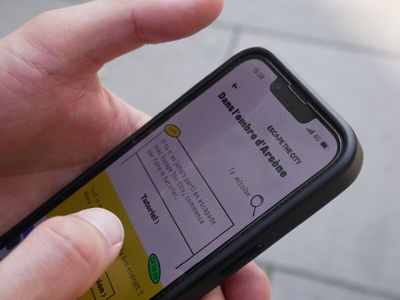Gros plan sur une main tenant un smartphone affichant une application de jeu urbain