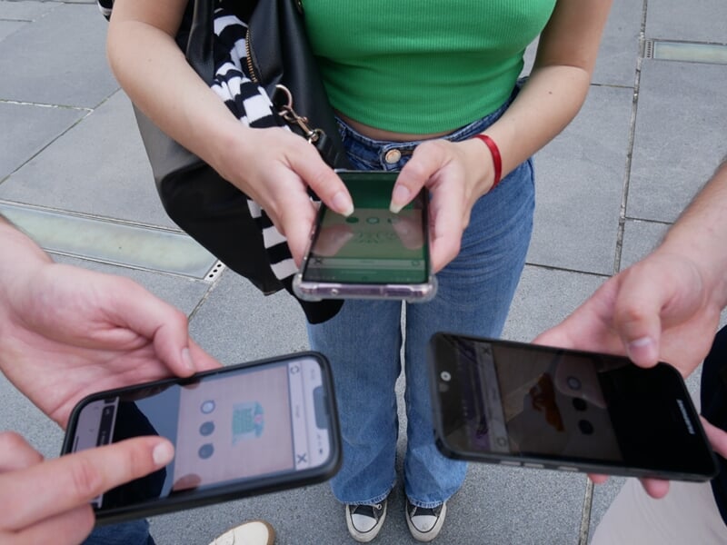 Groupe de trois personnes faisant un escape game sur smartphone