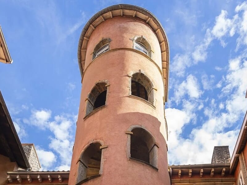Vue en contre-plongée de la tour rose de Lyon, bâtiment emblématique du Vieux-Lyon avec ses fenêtres cintrées et son ciel bleu en arrière-plan
