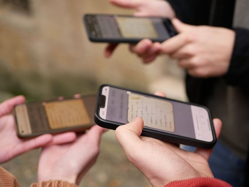 Gros plan sur plusieurs mains tenant des téléphones portables avec des notes affichées à l'écran.