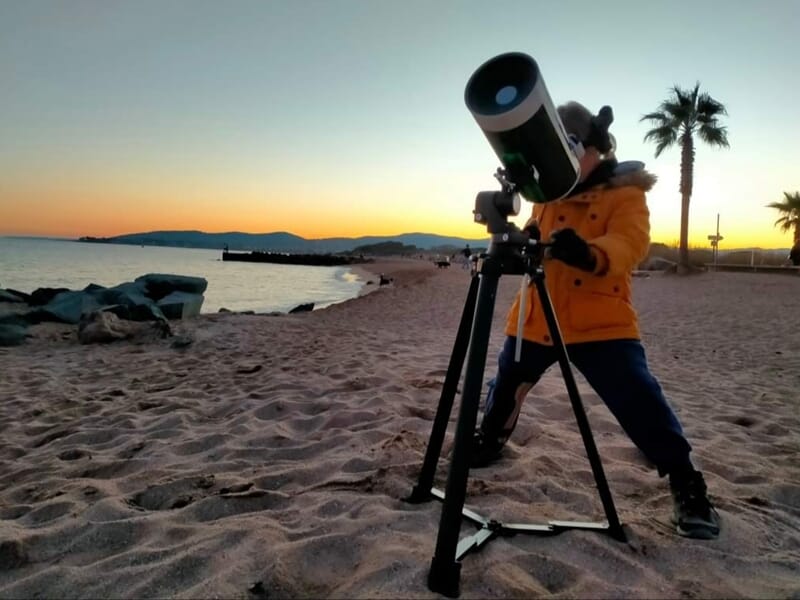 Personne utilisant un téléscope sur la plage