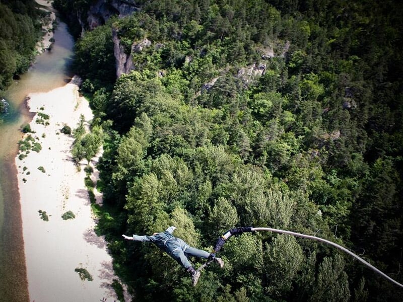 Personne en train de sauter à l'élastique, le fond se compose d'une plage et d'arbres