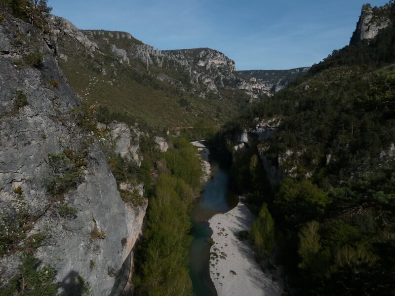 Personne en train de faire un saut à l'élastique au-dessus d'une rivière dans un paysage naturel verdoyant et montagneux.