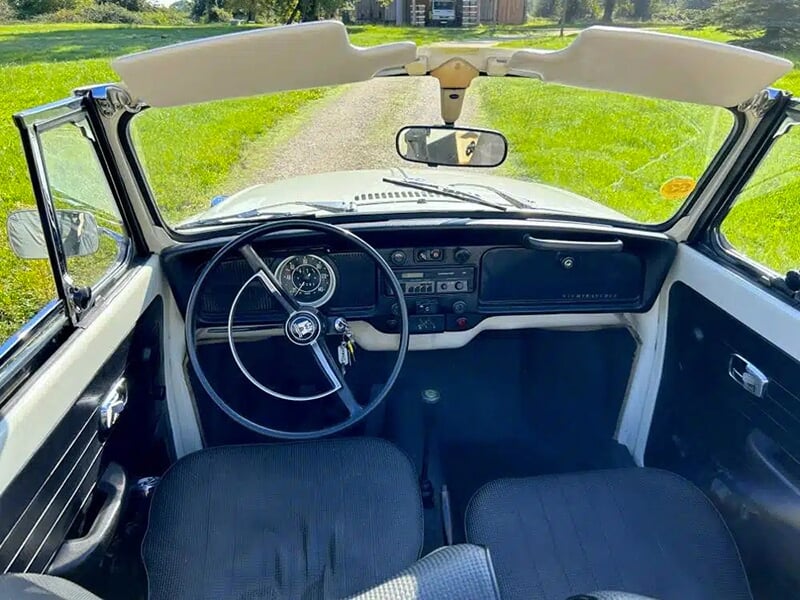 Vue intérieure d'une Volkswagen Coccinelle décapotable avec volant et tableau de bord vintage.