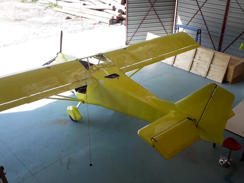 Image d’un avion léger jaune vif stationné dans un hangar, mettant en valeur son fuselage et ses ailes en détail.